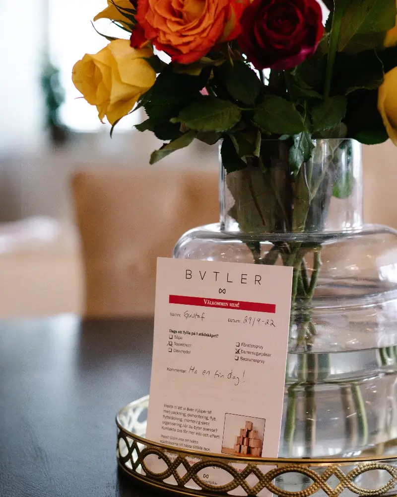 Personlig hälsning från bvtler uppställd bredvid en vas med rosor i ett varmt, välstädat hem.
