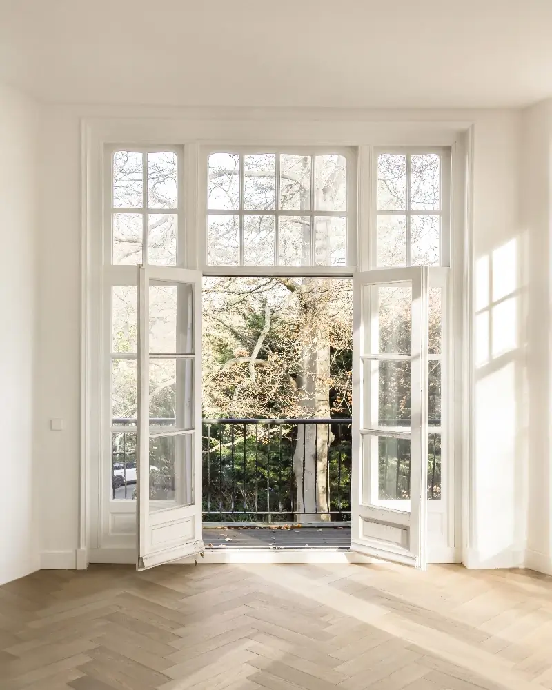 Öppna rena fönster där vårsolen strömmar in i ett ljust rum.