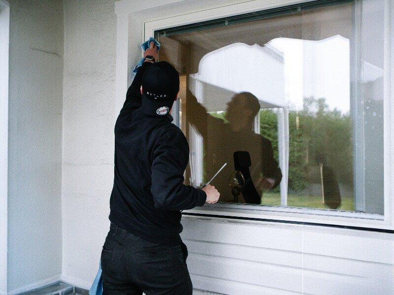 bvtler-medarbetare som putsar ett fönster utvändigt.