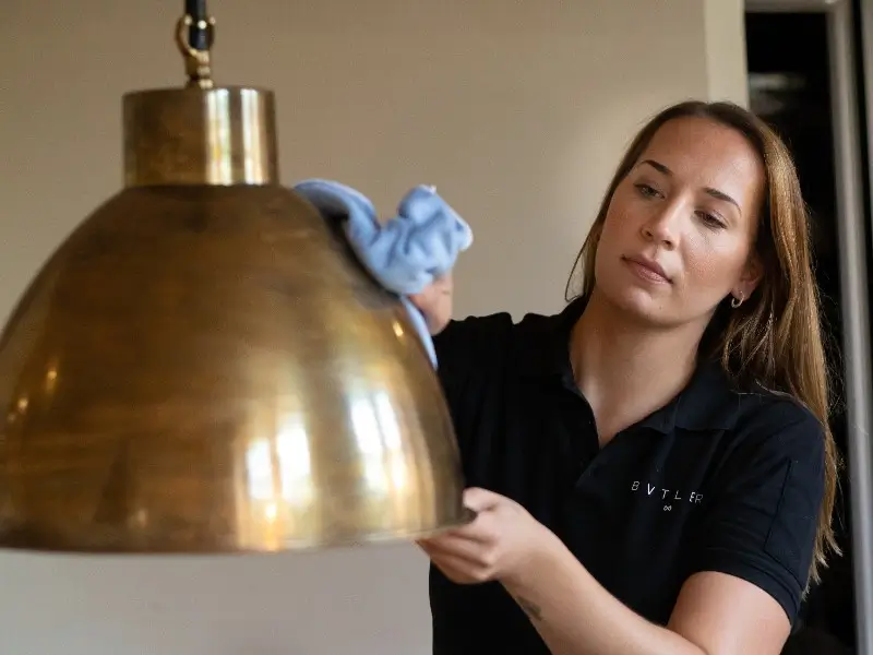 bvtler-medarbetare som noggrant putsar en mässingslampa i ett hem