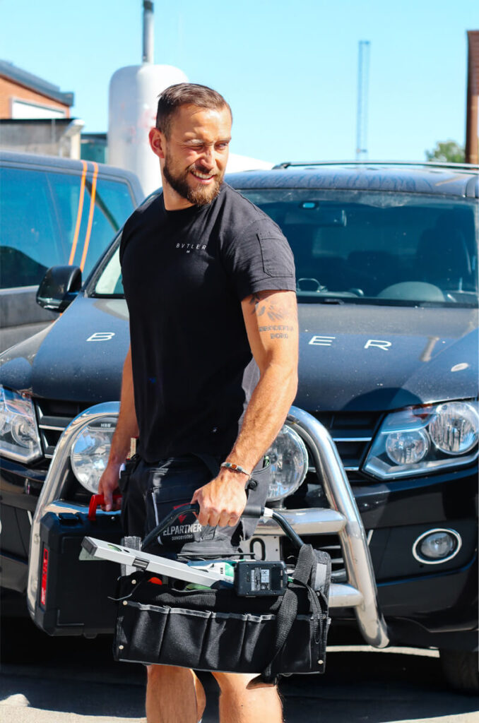 bvtlers handyman med verktygsväska utomhus framför servicebilen.